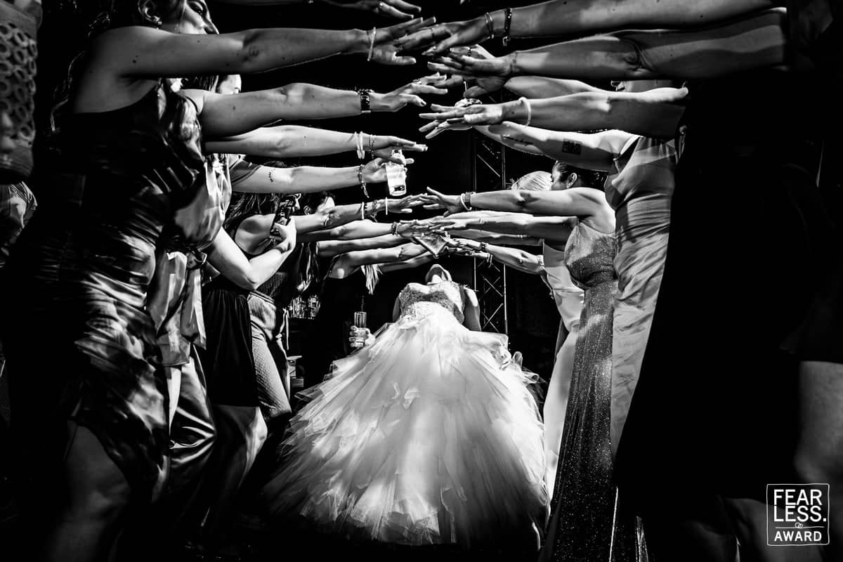 The bride walks through a tunnel of guests’ arms (black and white)