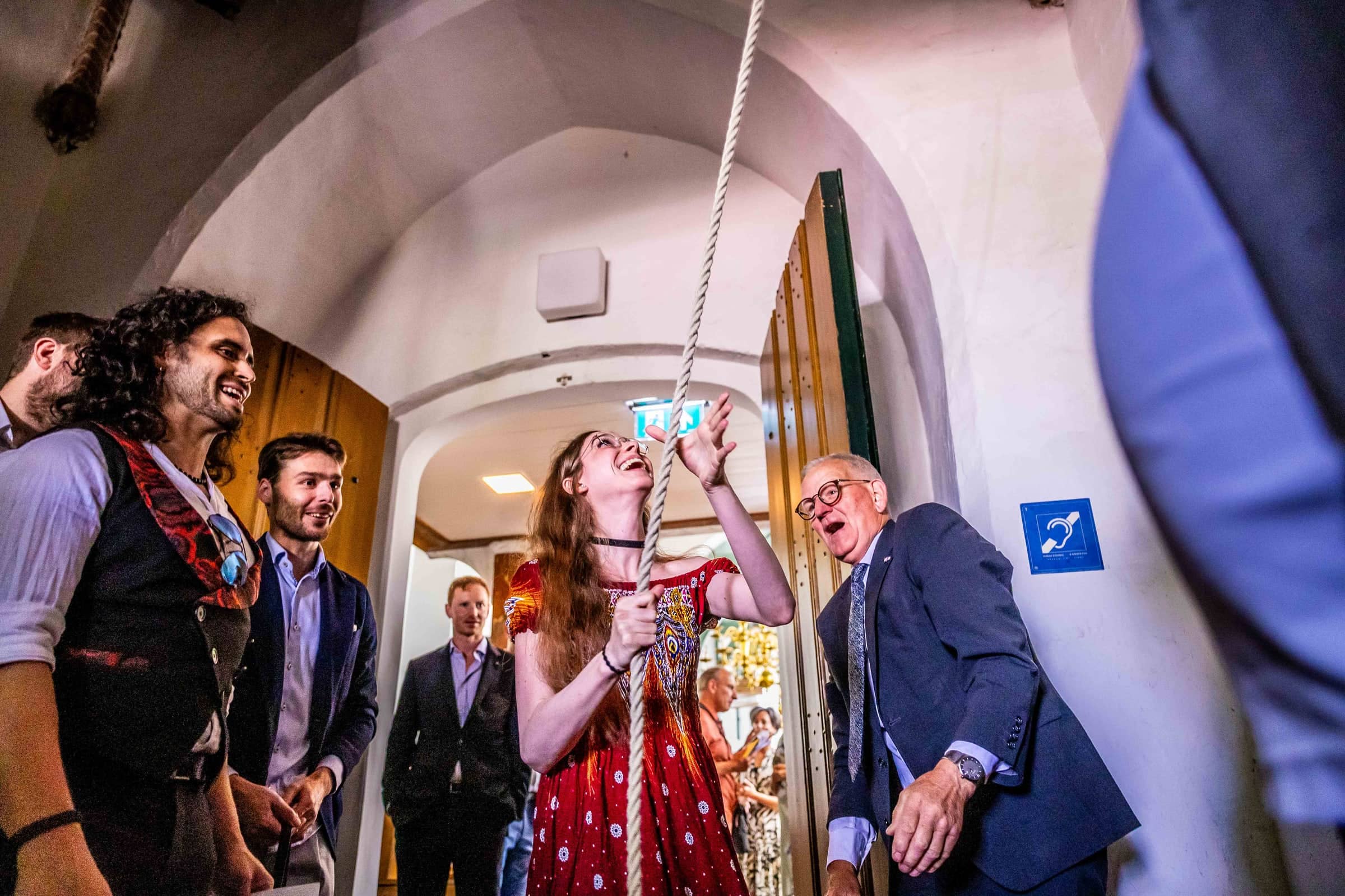 A guest rings the bell, laughing, as the family looks up
