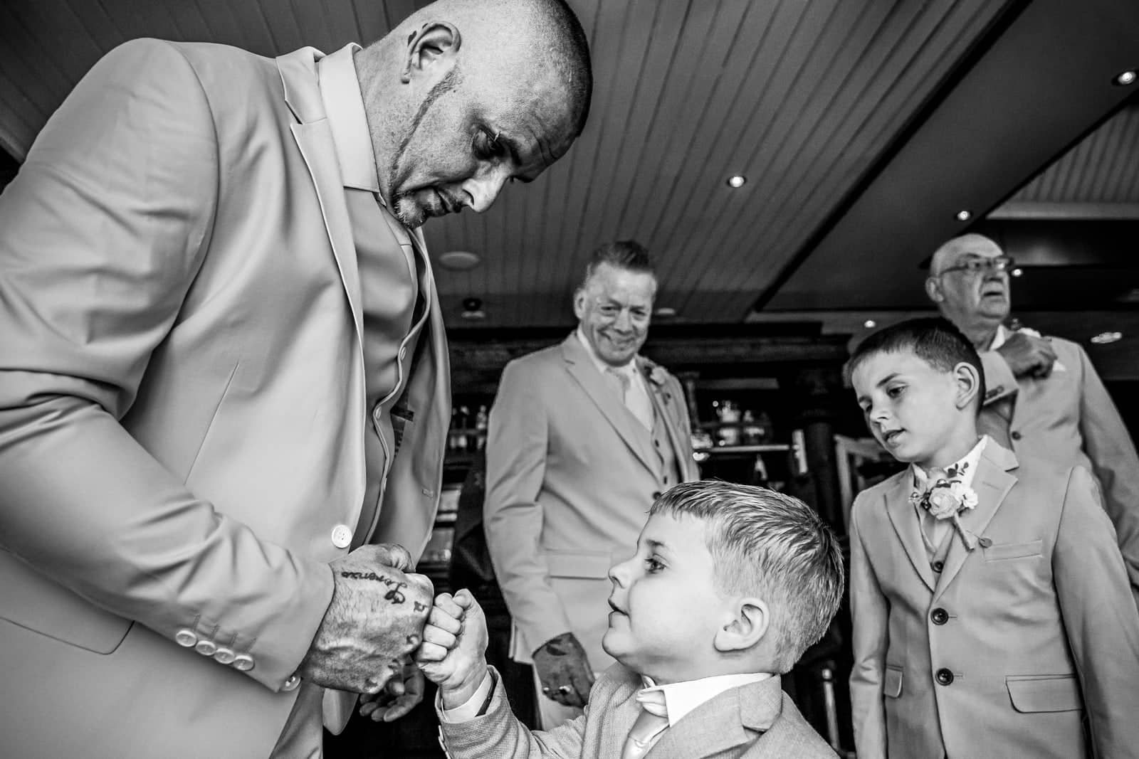 The groom fist-bumps a little boy (black and white)