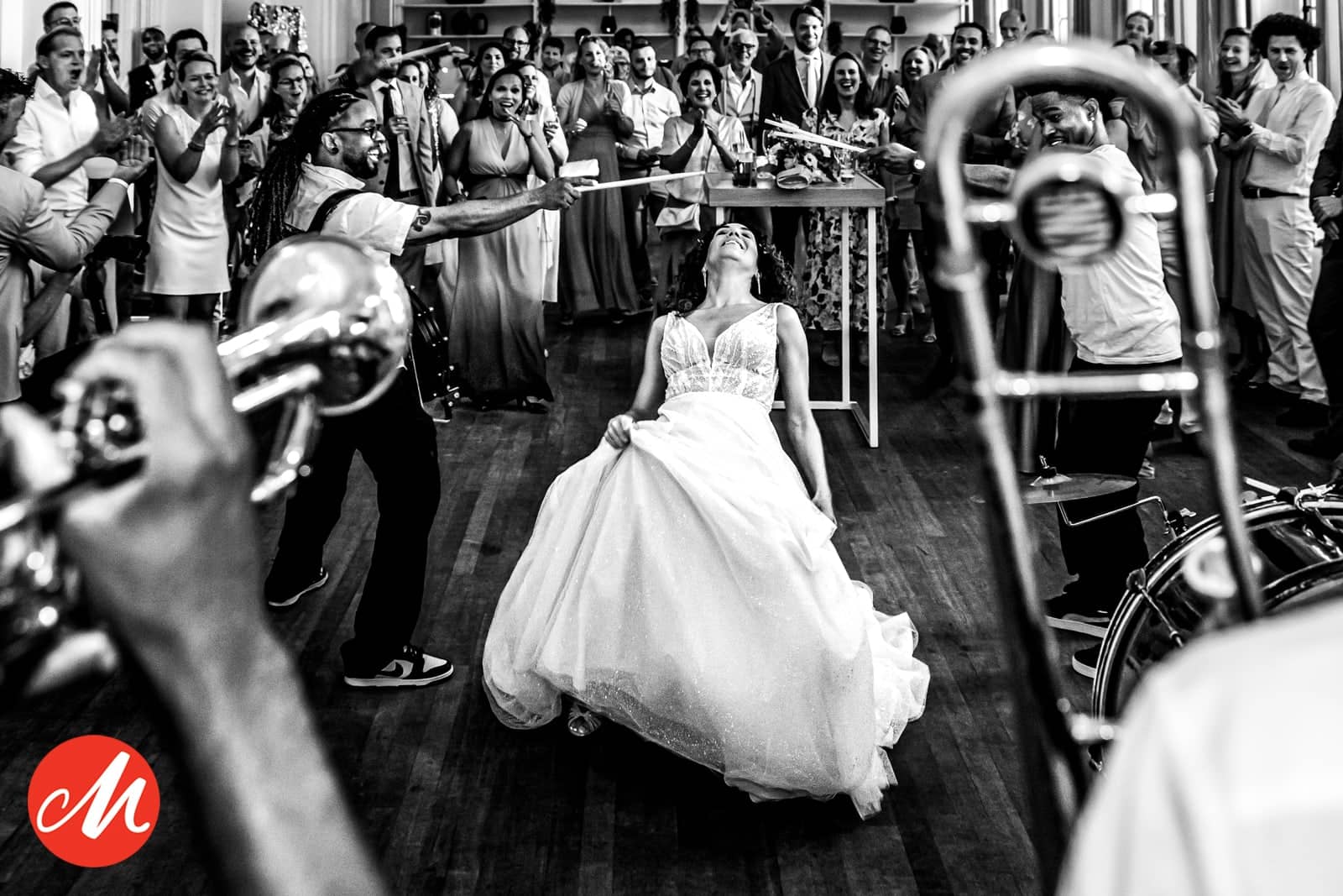 The bride dances exuberantly between trumpet and trombone players (black and white)