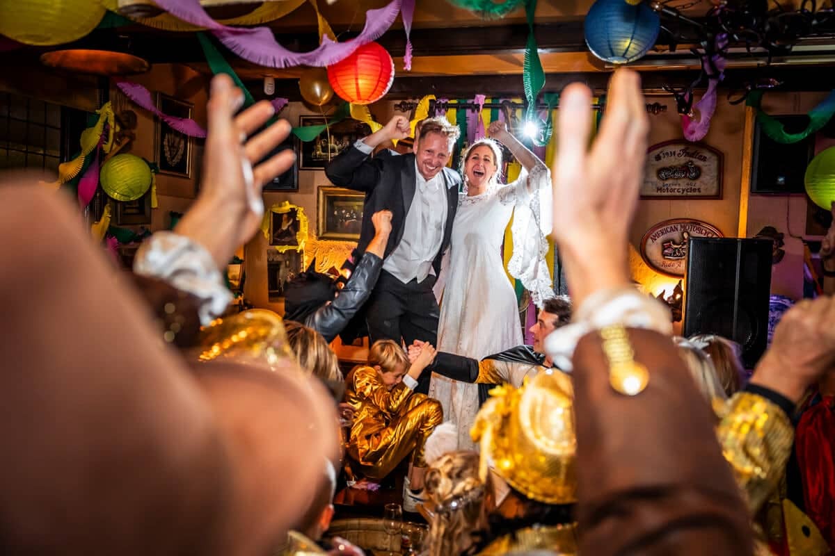 The couple among exuberant guests wearing gold gloves in a decorated pub