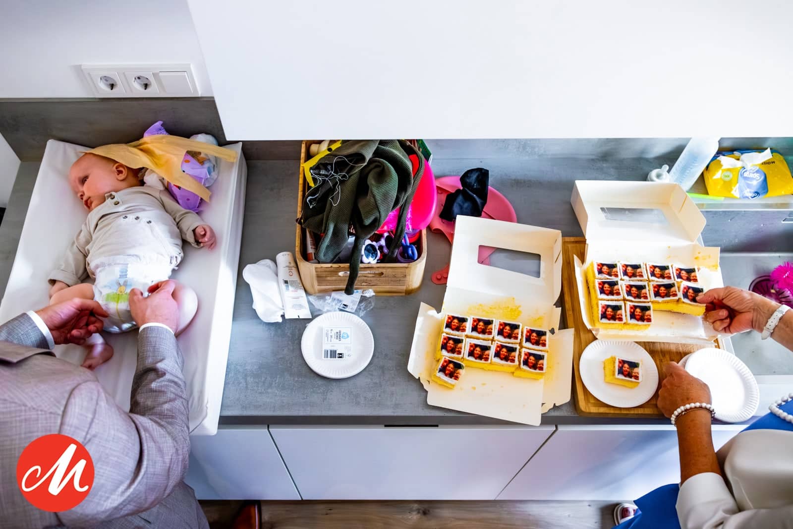 From above: a baby on the changing mat next to boxes of cake