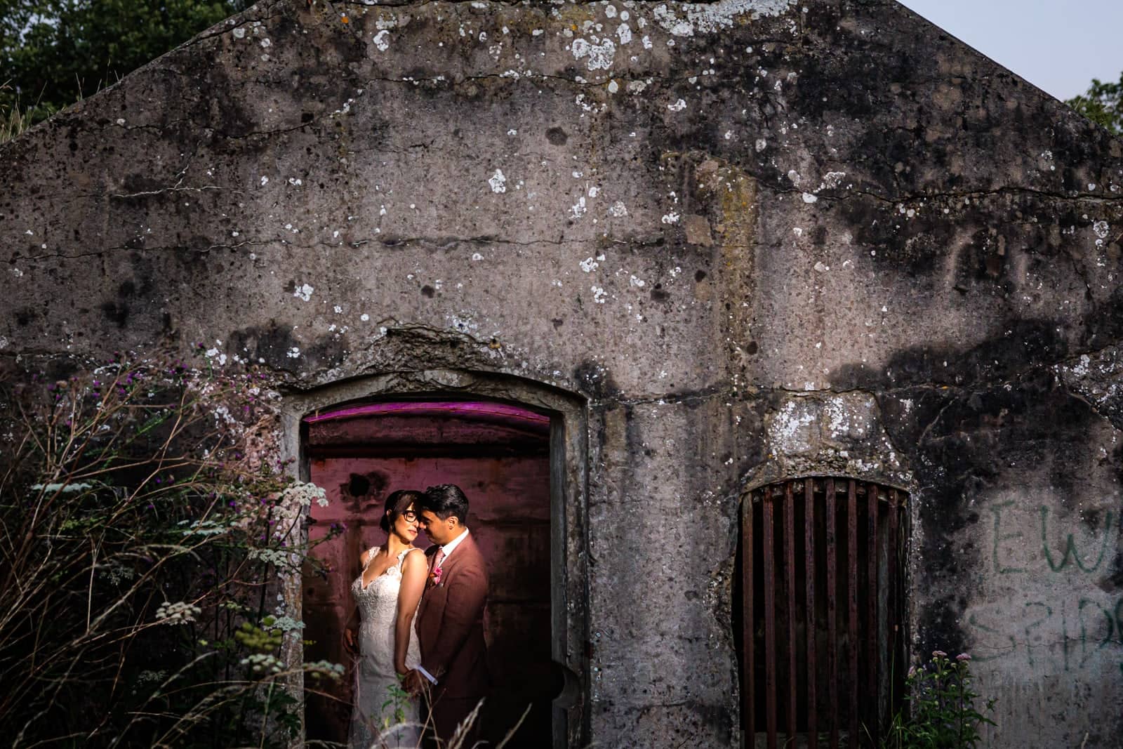 The couple in an old stone doorway, lit by pink light