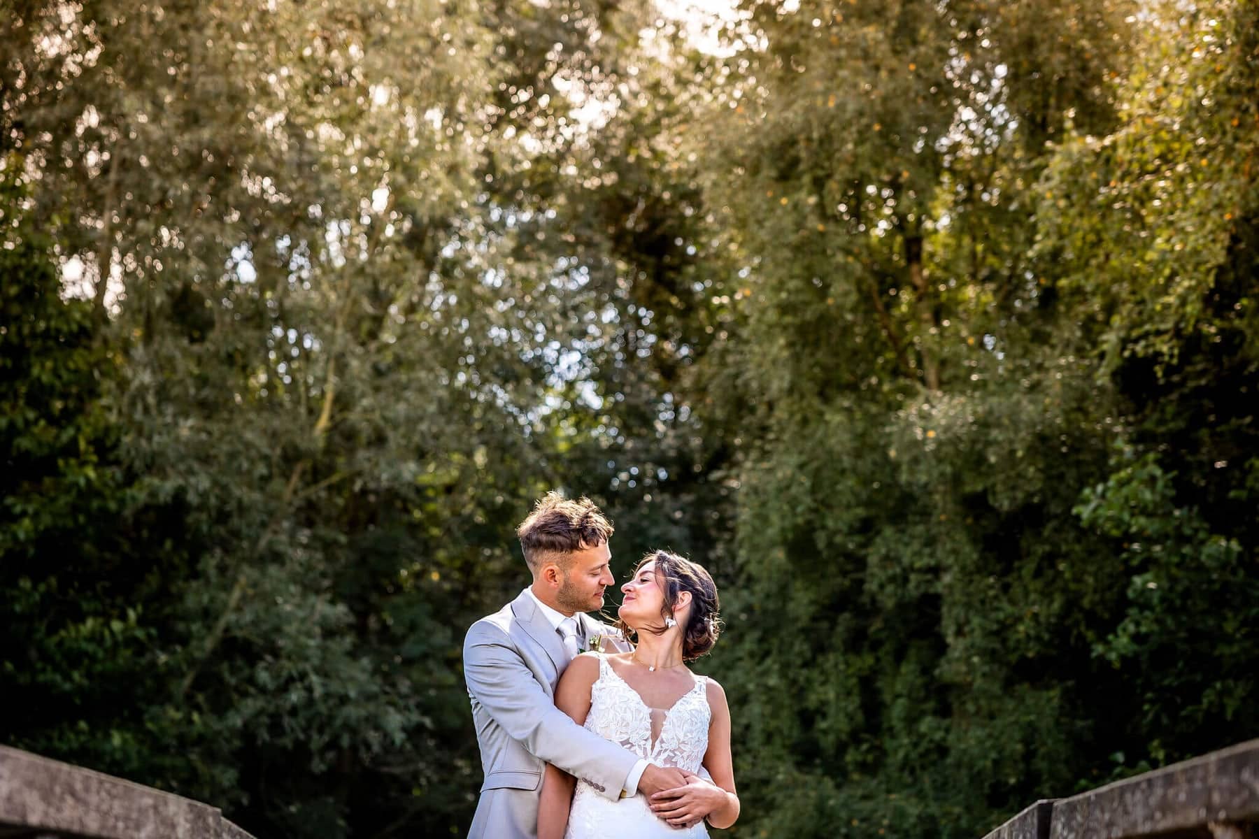 Couple embracing in front of a wall of greenery in the late sunlight