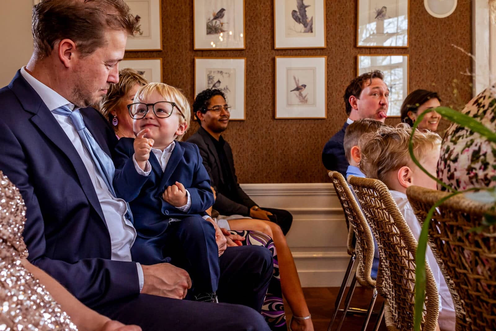 A little boy in glasses bursts out laughing on a lap during the ceremony