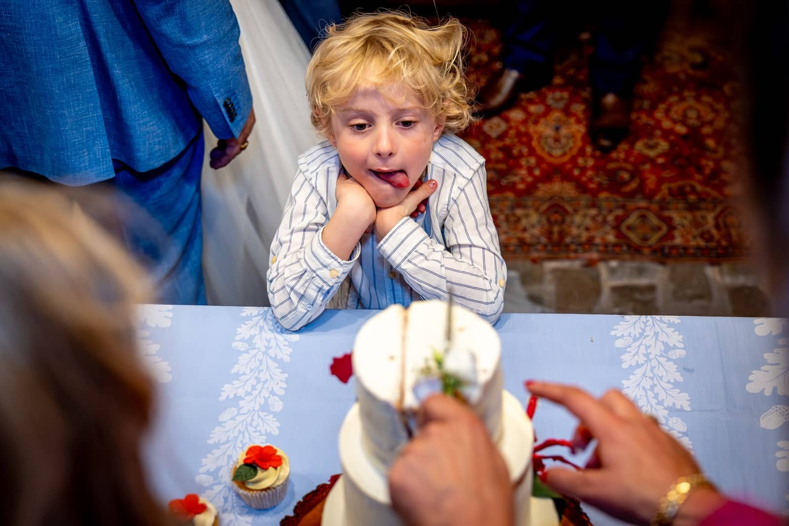 A boy sticks his tongue out at the wedding cake