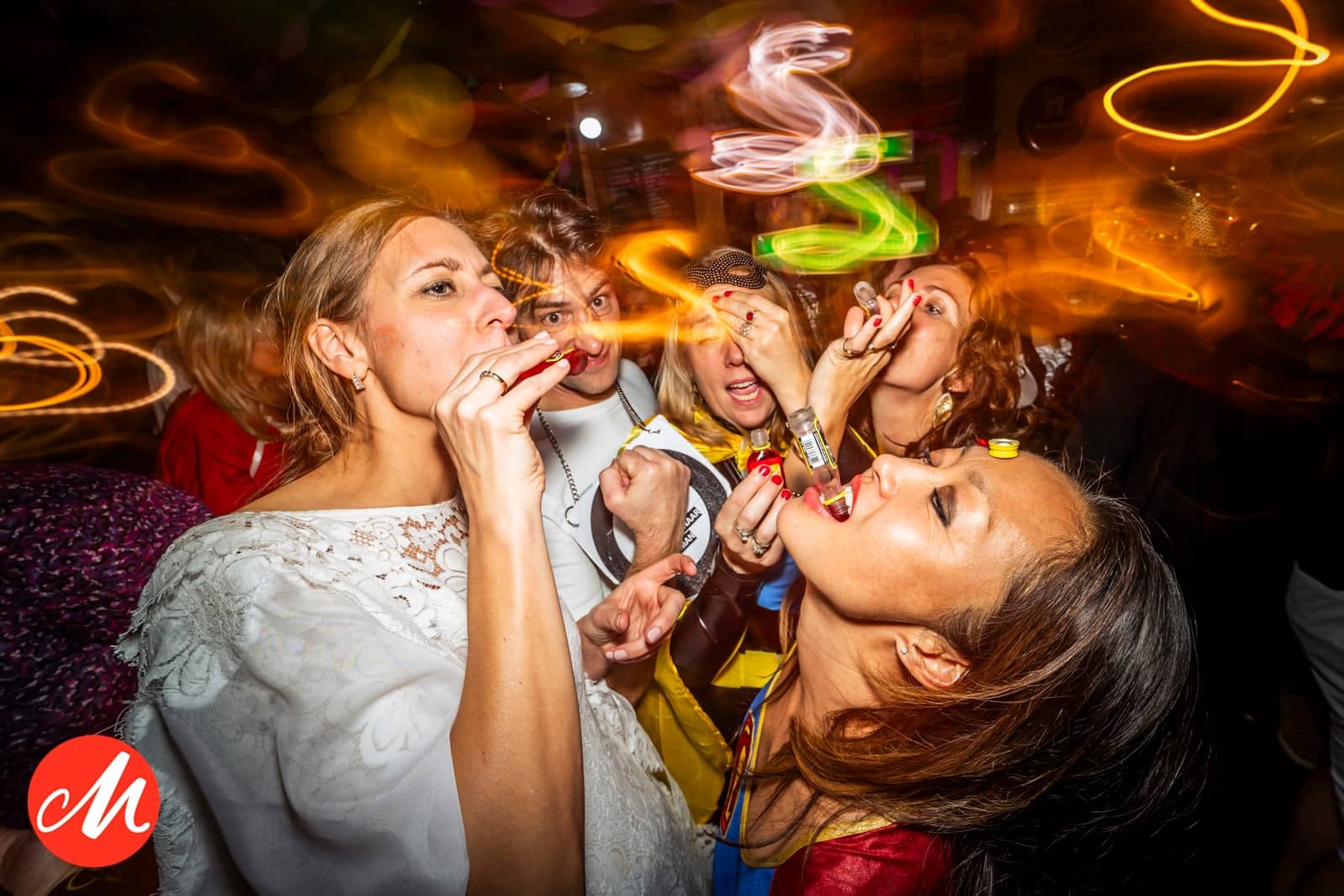 The bride and guests blow party horns amid colourful light trails