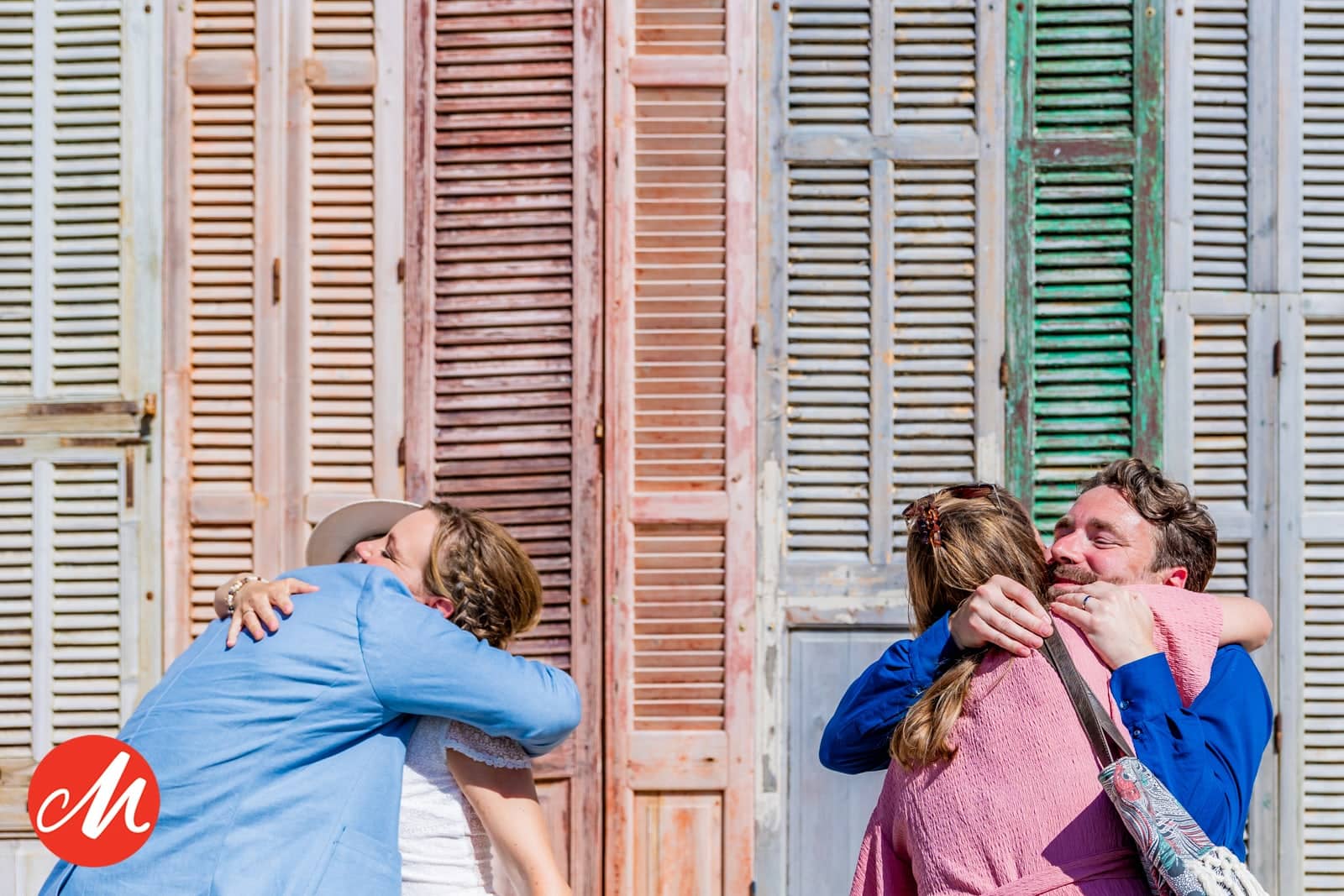 Two hugs in front of old, weathered wooden shutters in pastel colours