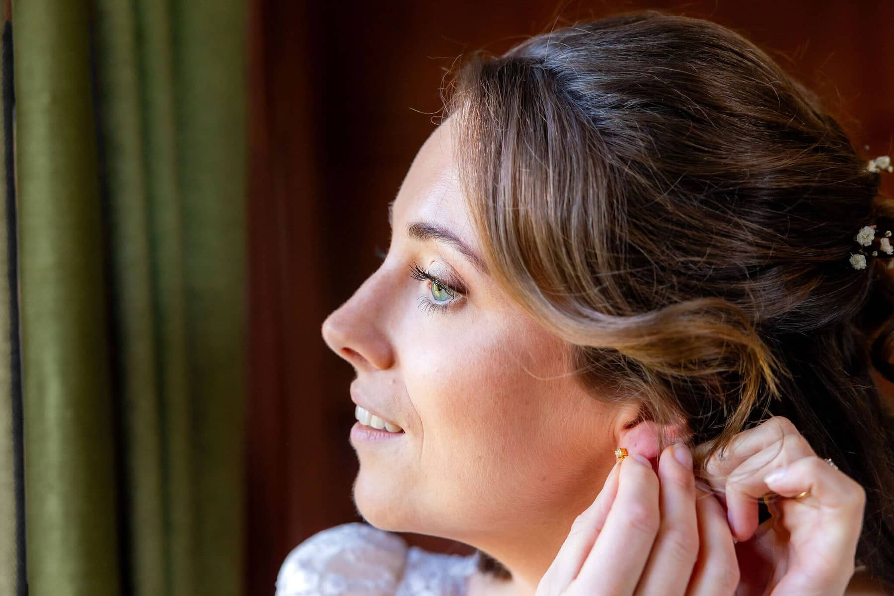 The bride putting in her earring in soft side light