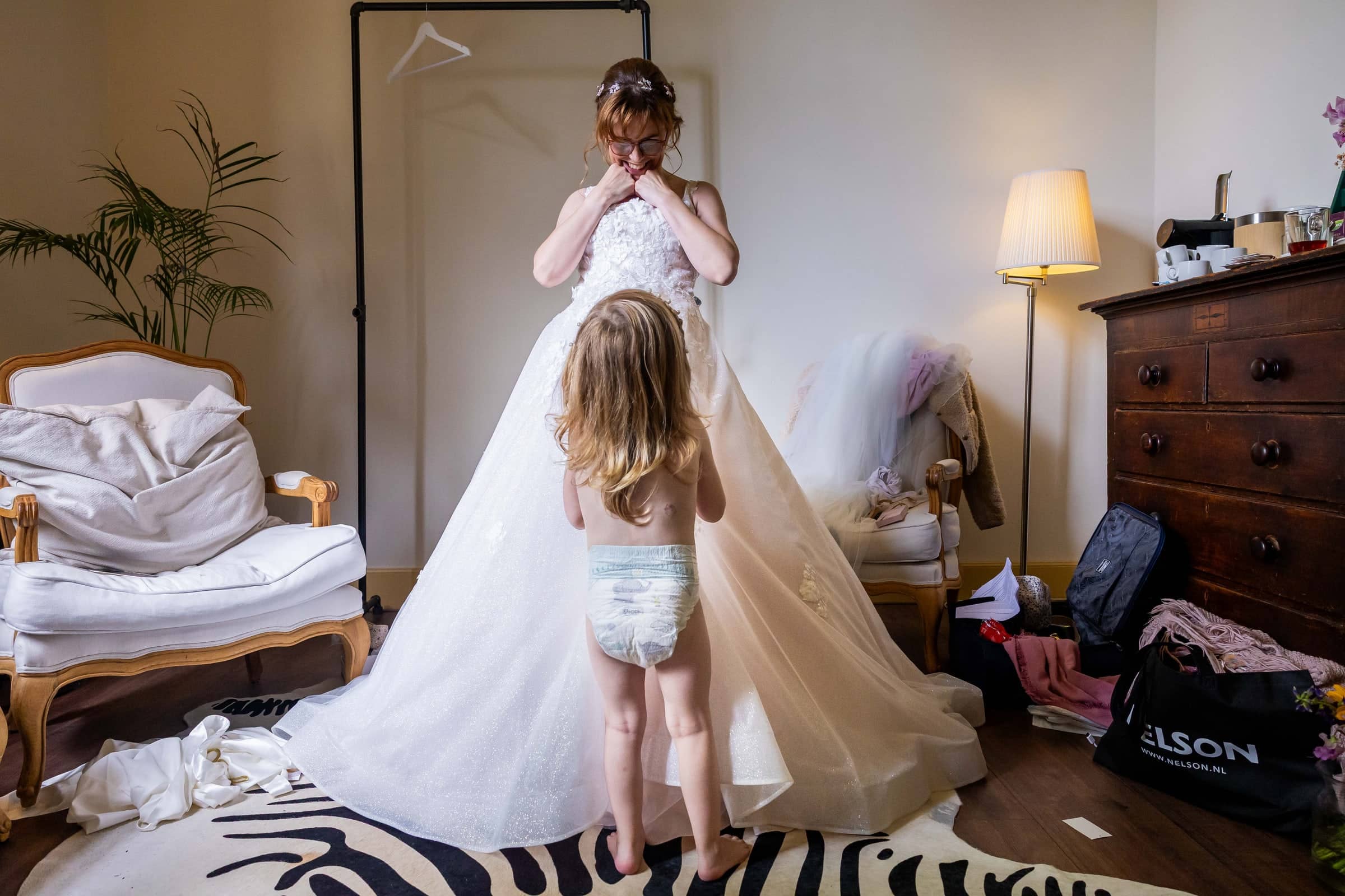 A toddler in a nappy looks up at the bride in her wedding dress