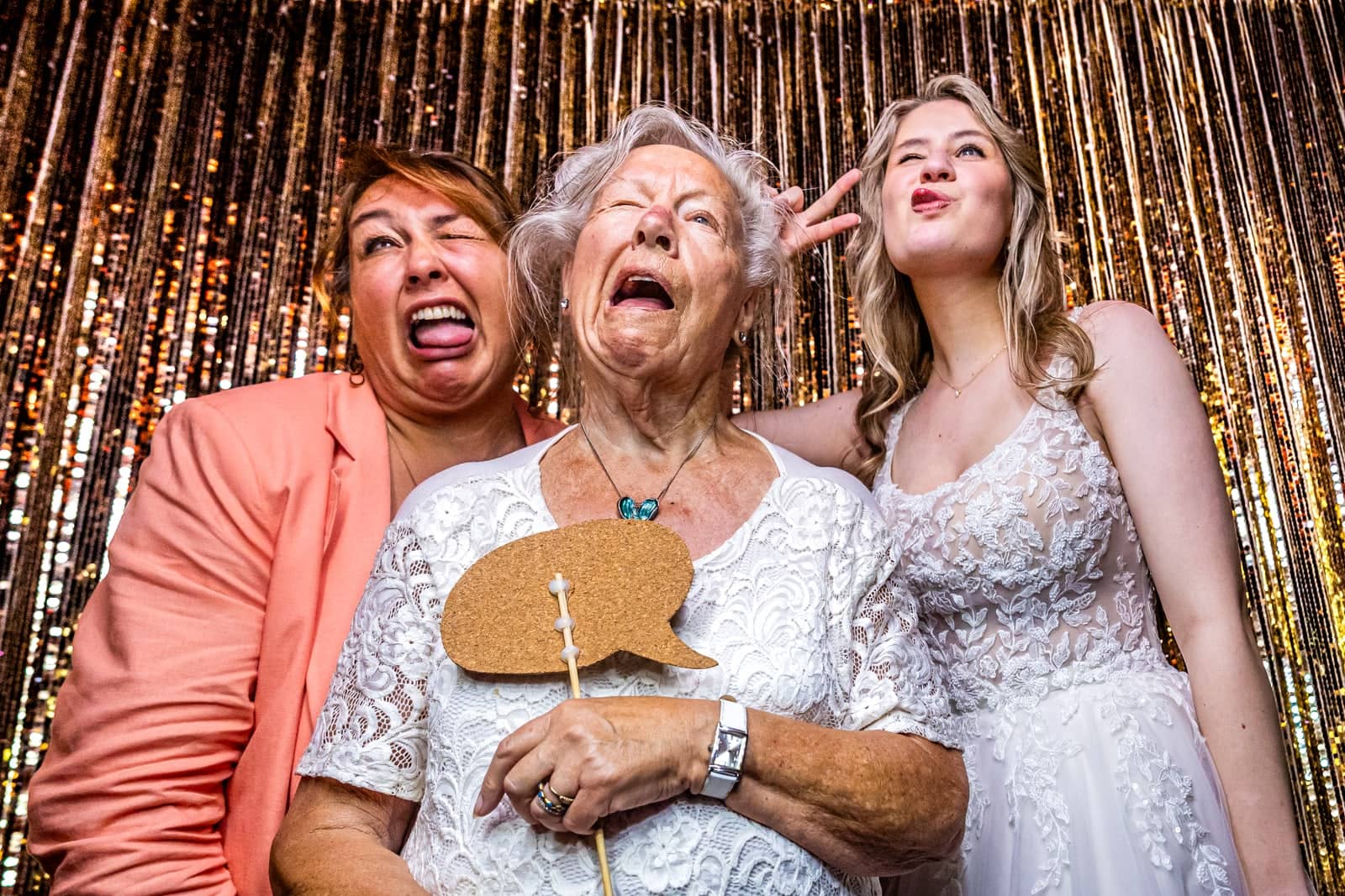 Grandma pulls a funny face in the photo booth with the bride and a guest