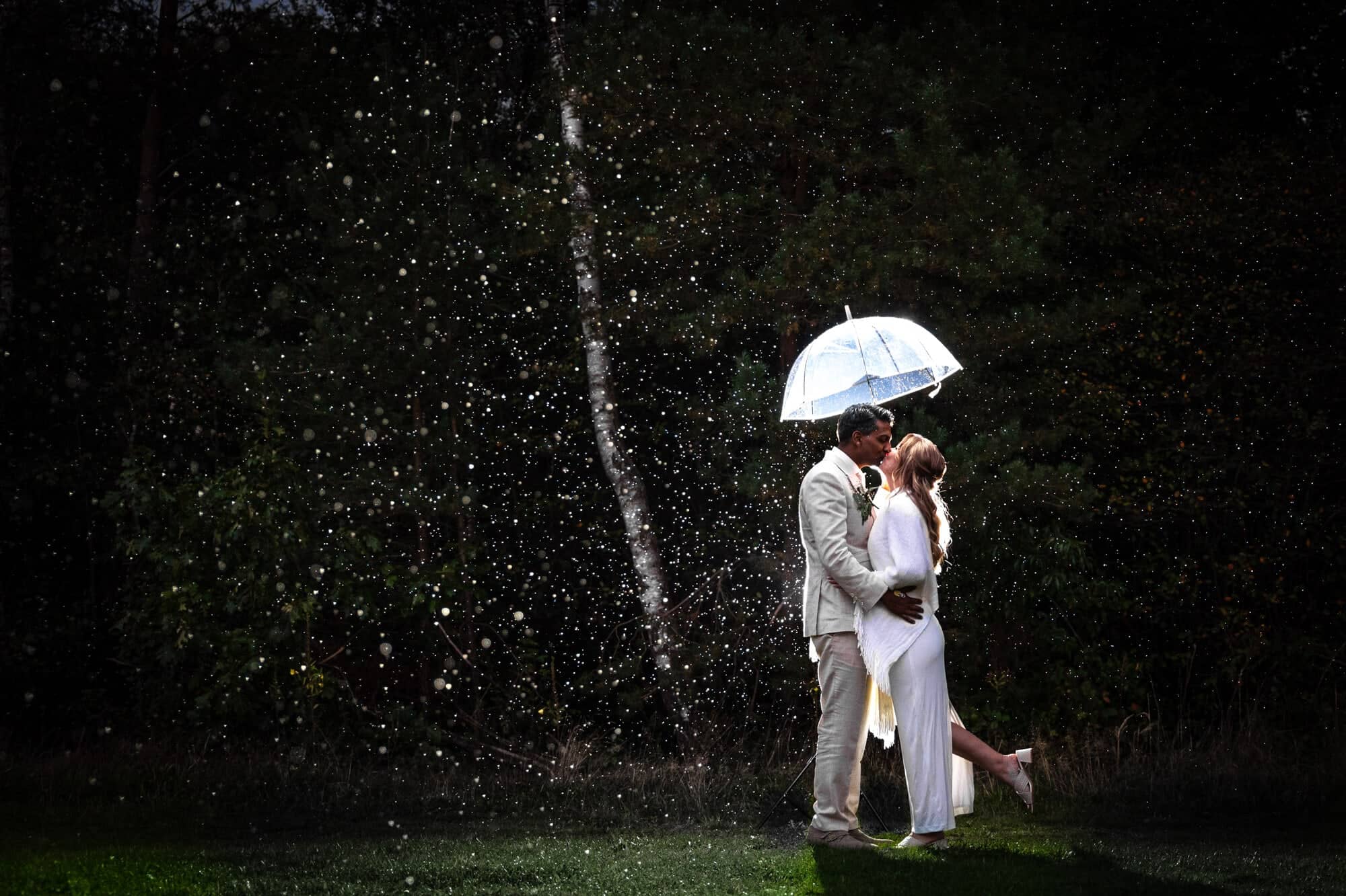 Couple kissing under a clear umbrella in the rain at Brasserie Zonnestraal in Hilversum