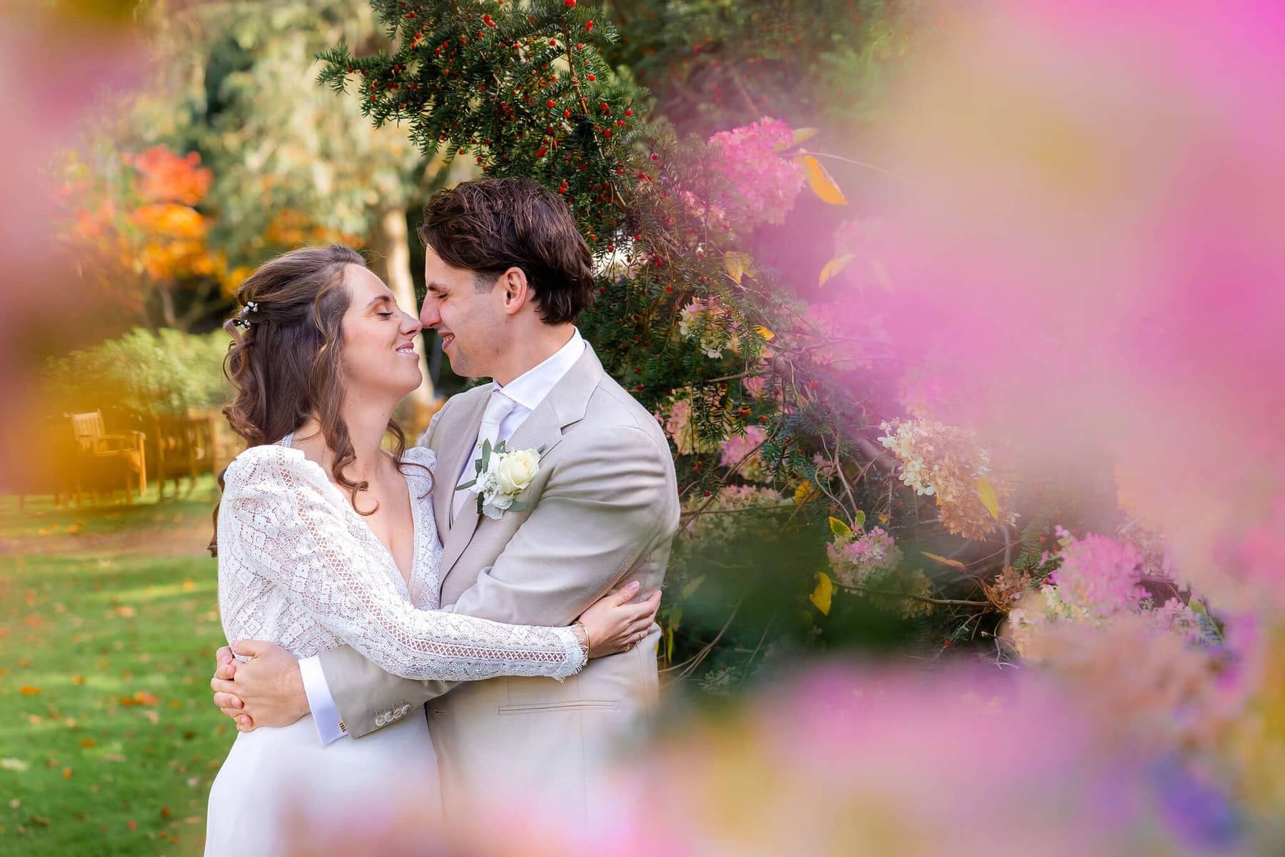 Couple embracing, framed by soft-focus pink flowers