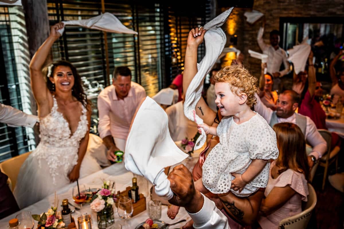 The bride and a toddler twirl napkins during the wedding dinner