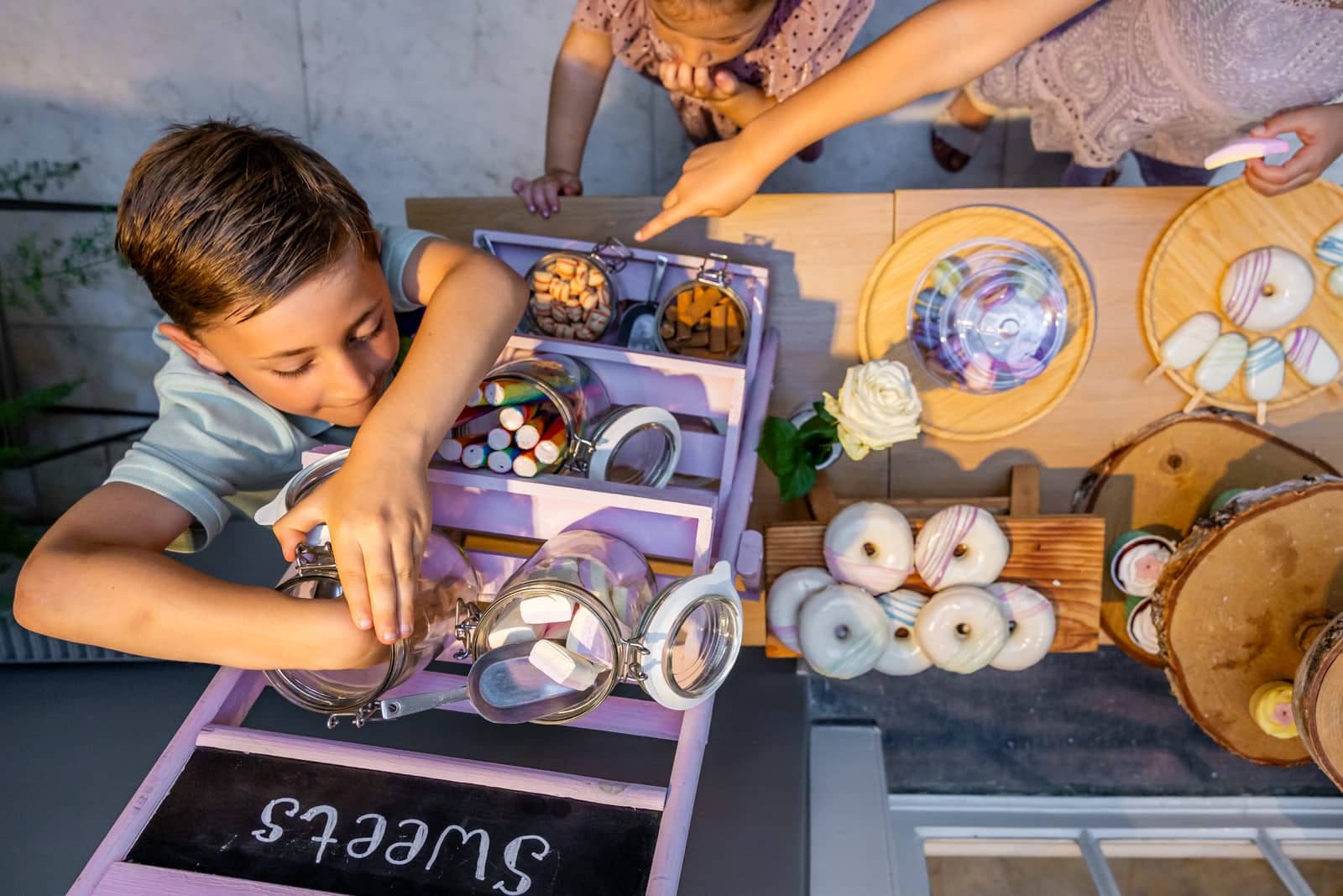 From above: a boy dips into the jars of a purple sweets cart