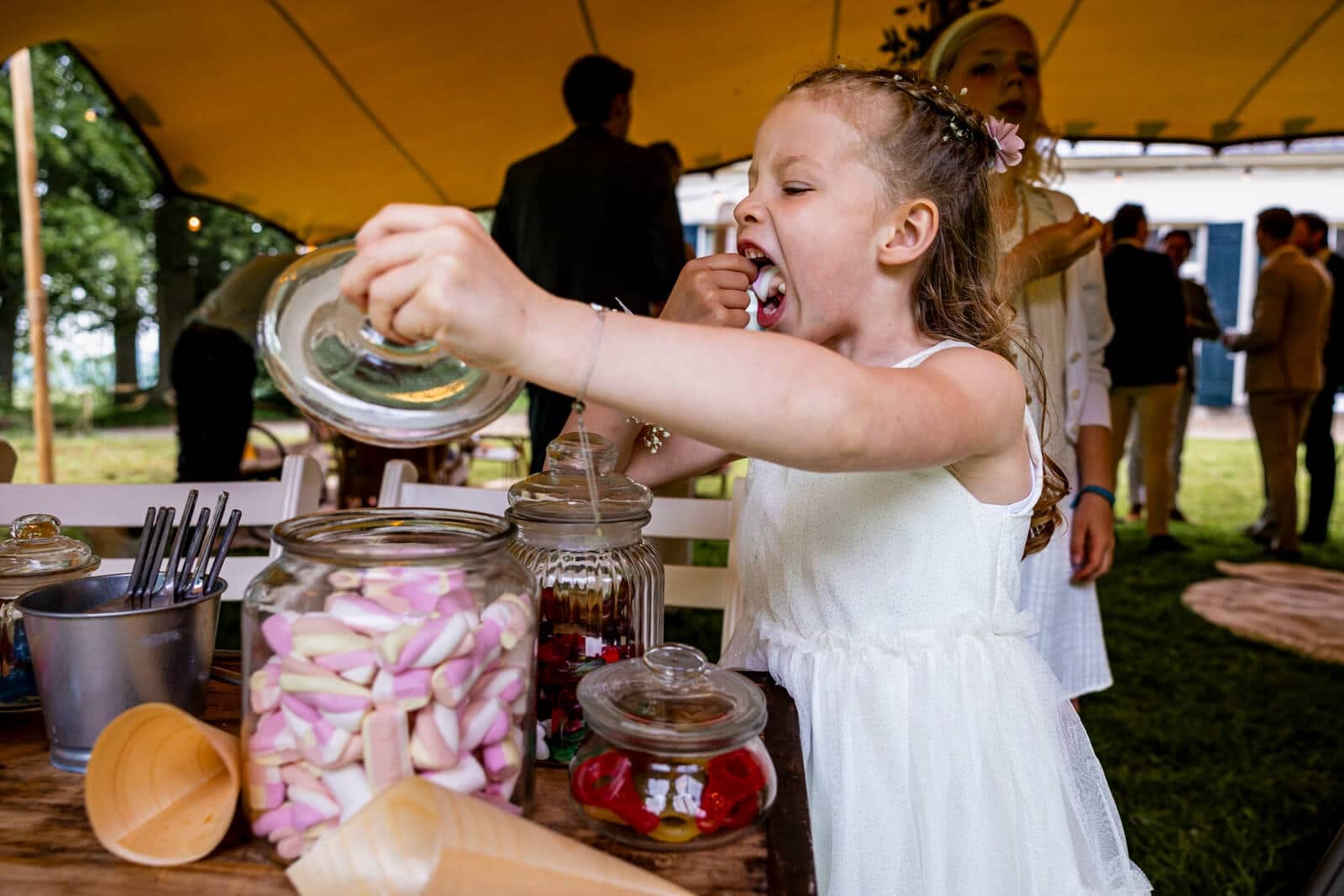 A girl stuffs a marshmallow into her mouth at the sweets table