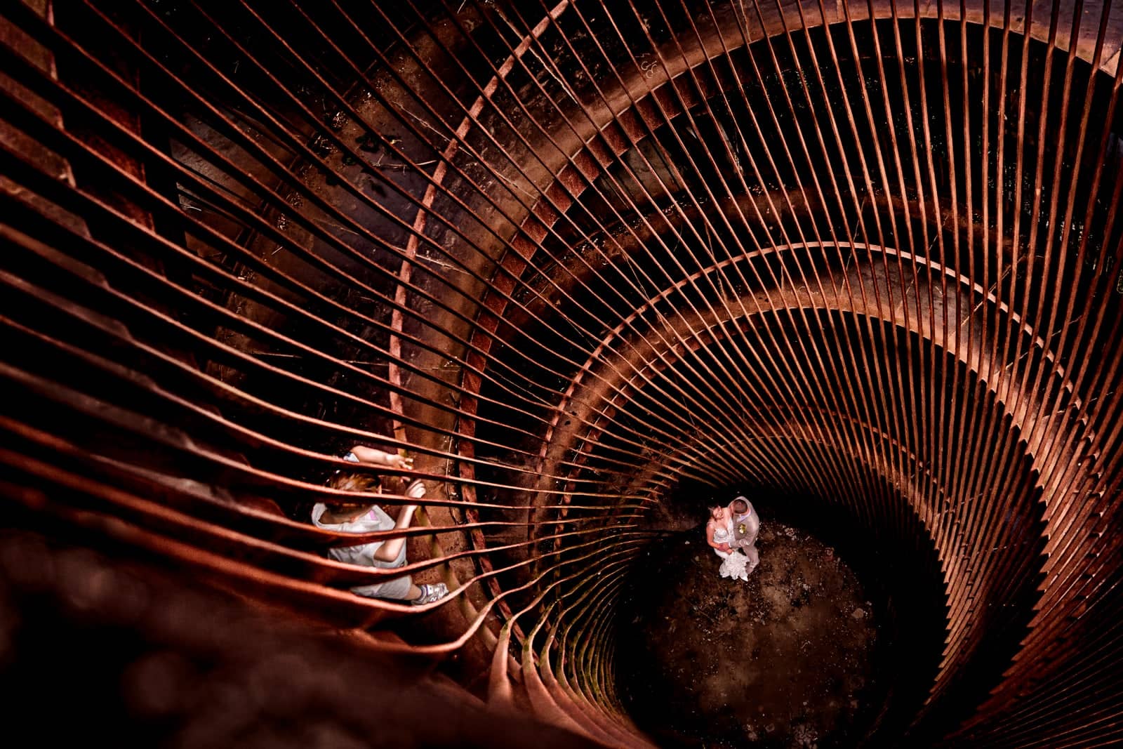 Couple at the bottom of a copper spiral, photographed from above