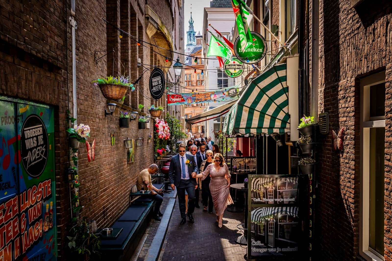 The couple and guests walk through a narrow alley full of cafés and flags