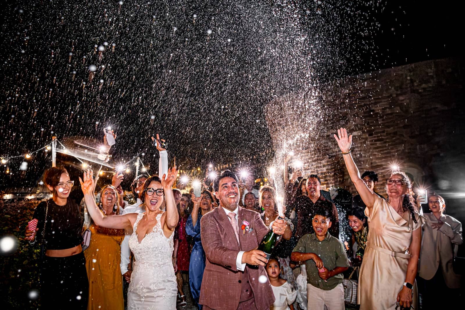 The couple and guests cheer in a shower of champagne and sparklers
