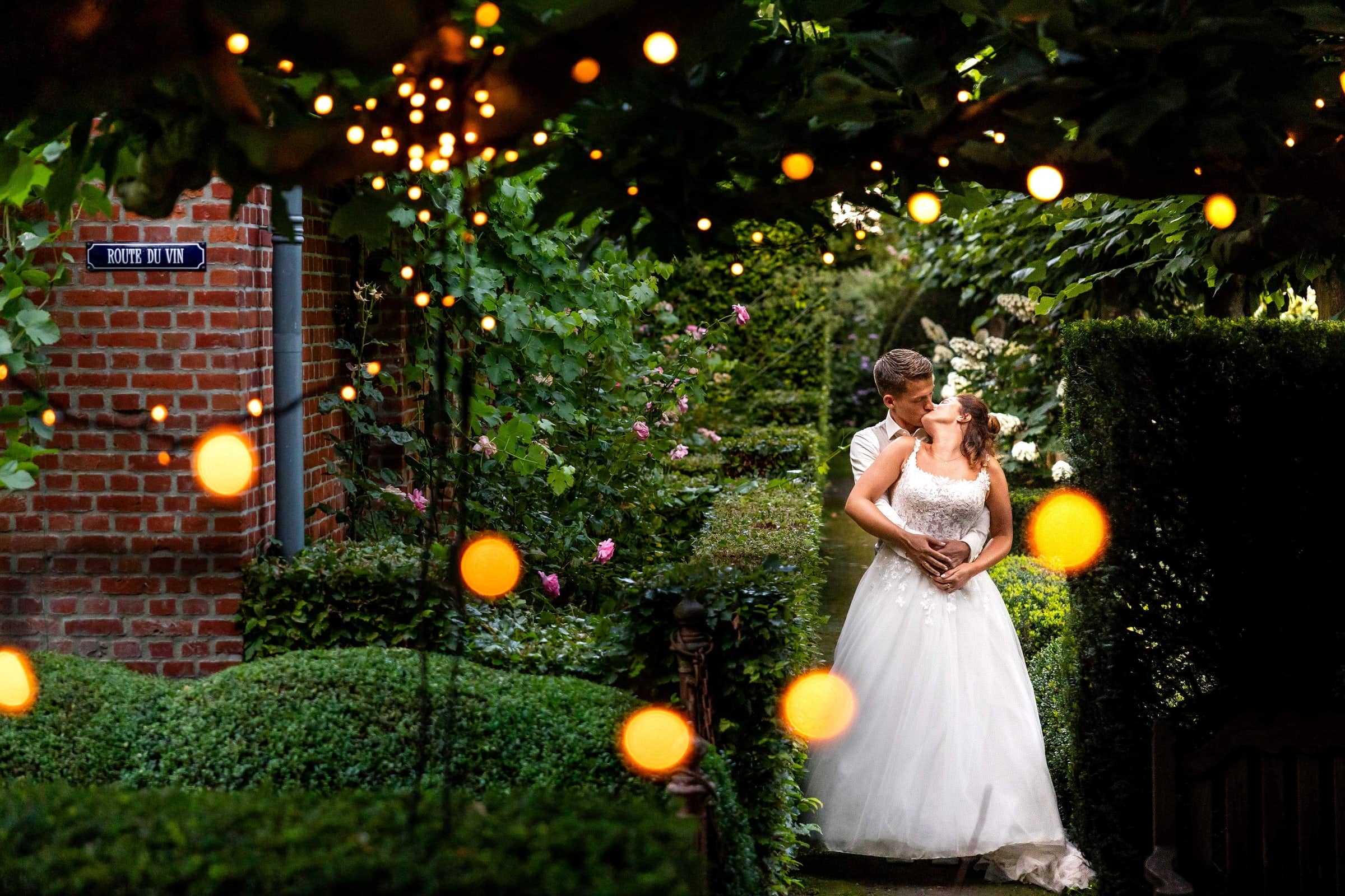 Couple kissing in a garden full of string lights